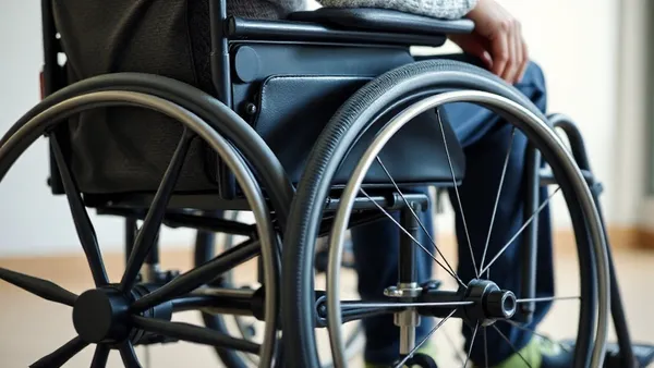 Pessoa usuária de cadeira de rodas com equipamentos de tecnologia assistiva ao redor